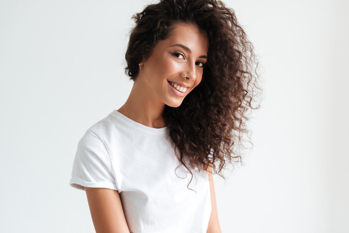 Mujer con cabello rizado definido tras usar el activador de rizos sin aclarado Curly Care de Thader Pharma.